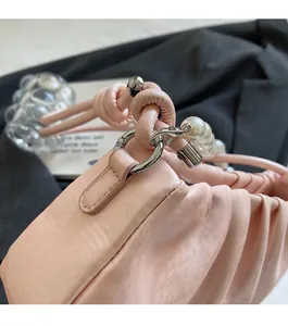 Detailed shot of silver metal rings and white pearls on pink ruched handbag