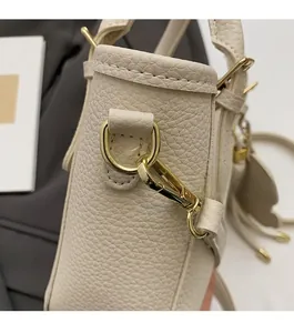 Detail of beige lychee leather texture and golden metal D-ring buckle on bucket bag