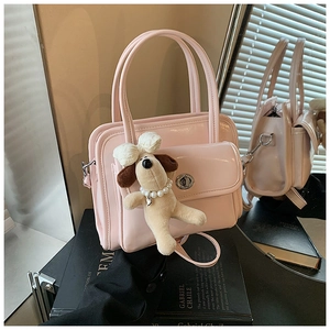Pink patent leather handbag featuring a cute plush dog charm and silver twist lock detail