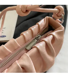Detail of smooth silver metal zipper on pink pleated faux leather cloud handbag