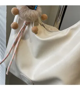 Dettaglio borsa tote bianco crema con pompon marrone e morbida texture in PU plissettato
