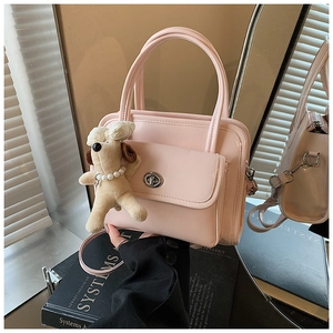 Pink glossy handbag detail showing silver turn-lock pocket and cute plush puppy charm