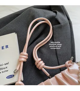 Detail of adjustable shoulder strap and white pearl decor on pink pleated cloud bag