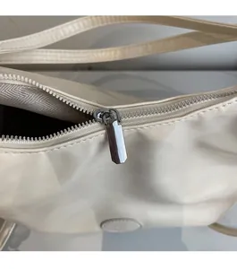 Dettaglio della cerniera in metallo argentato e trama in ecopelle beige con fodera