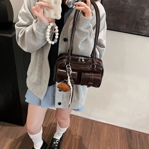 Dark brown shiny leather pillow bag with double pockets and plush charm shown on a model