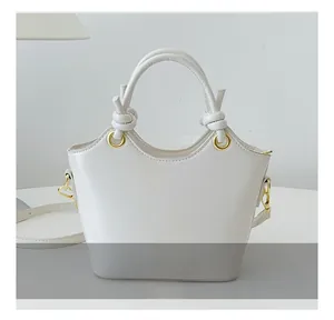 Detailansicht des runden Griffs mit Knotendesign und Goldringen an der beigen Handtasche