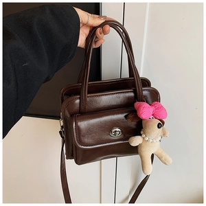 Detail of coffee brown PU leather handbag featuring silver twist lock and puppy charm