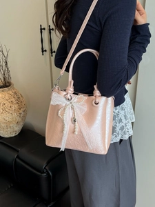 Sac seau rose perlé avec nœud en dentelle et perles porté par un mannequin
