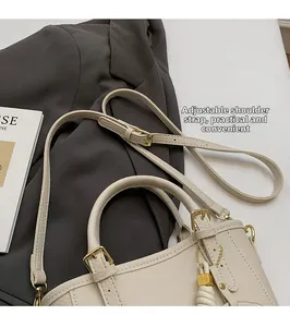 Close-up of adjustable strap and pebble grain texture on beige handbag with gold hardware
