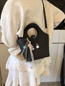 Black lychee texture bucket bag with round handles and trendy bag charms displayed on model