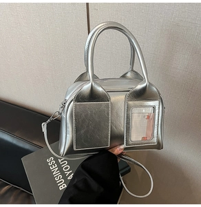 Detail of silver metallic pillow bag featuring a transparent card slot and top handle