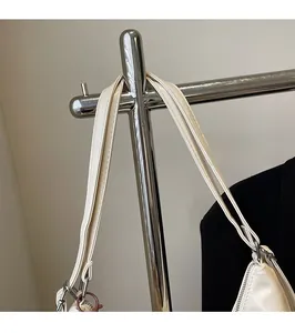 Dettaglio della tracolla regolabile con fibbie argentate su borsa tote beige