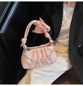 Detail of pink pleated satin handbag featuring pearl chain and knotted rope handle