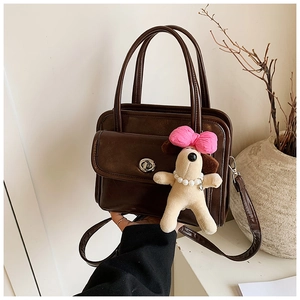 Close-up of vintage brown leather handbag with metal twist lock and cute plush puppy charm
