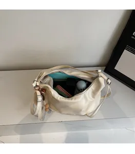 Spazioso interno della borsa tote in ecopelle color crema con ciondolo a pompon