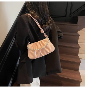 Detail of pink ruched cloud bag featuring elegant faux pearl strap and soft PU texture