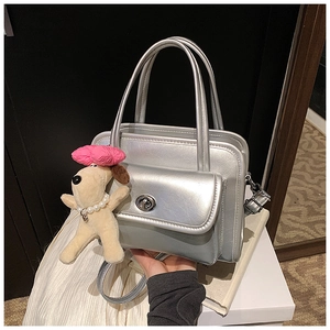Detailed close-up of a silver metallic handbag with a cute plush puppy charm accessory