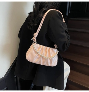 Close-up of pink pleated crossbody bag with large pearl chain and knotted shoulder strap