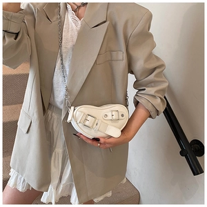 Détail du sac à bandoulière beige en forme de cœur avec cuir et clous métalliques