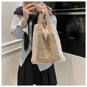 Detail of beige crochet tote bag with colorful pearls shown in a casual lifestyle setting