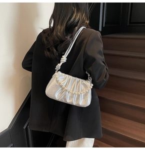 Detail of silver pleated crossbody bag with large faux pearl chain and knot shoulder strap