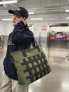 Green nylon tote bag with black webbing grid and adjustable shoulder strap for daily use
