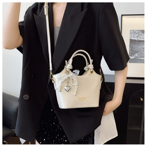 Detail der beigen Bucket Bag aus Kunstleder mit Spitze, Perlen und Herzanhänger