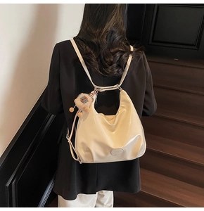 Dettaglio della borsa lucida color crema con un simpatico ciondolo a leone di peluche