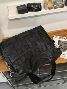 Large black nylon tote bag with woven patchwork design and adjustable shoulder strap