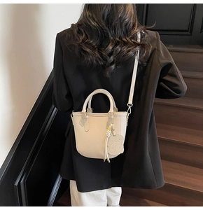 Detail of cream white bucket bag featuring pebble leather texture and cute animal charm
