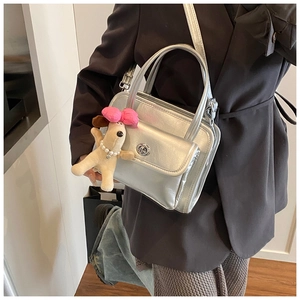 Detail of silver metallic handbag featuring turn-lock closure and cute puppy charm