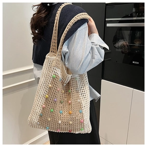 Close-up of cream knit tote bag with colorful pearl embellishments and woven texture
