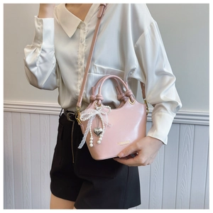 Detail der rosa PU-Leder Eimertasche mit Herzanhänger, Perlen und Spitzen-Schleifen-Akzent