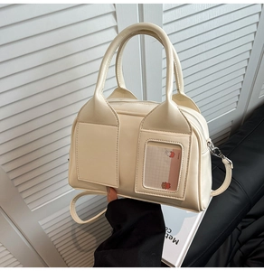 Dettaglio della borsa Boston crema con doppi manici e scomparto per carte frontale