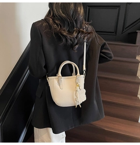 Detailed back view of a white pebble leather bucket bag worn as a crossbody on stairs
