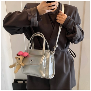 Silver metallic handbag featuring a cute plush puppy charm and versatile shoulder strap