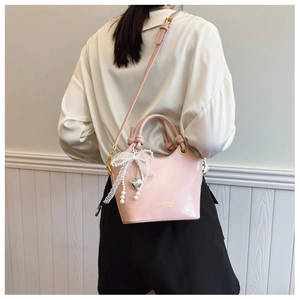 Detail der rosa Beuteltasche mit Spitzenschleife, Perlenanhänger und Schultergurt