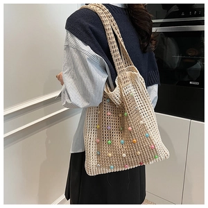 Detail of beige crochet tote bag with colorful pearl beads on a model shoulder