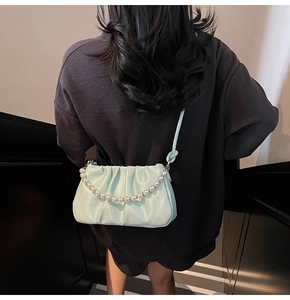Back view of model wearing a mint green pleated cloud bag with elegant pearl chains