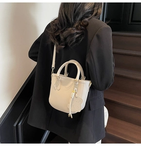 Detail of creamy white lychee grain leather mini tote bag with bear charm and gold hardware