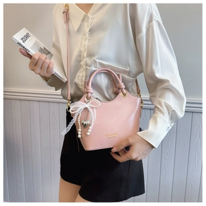 Details der rosa Eimertasche mit Spitzenschleife, Perlenkette und Herz-Metallanhänger