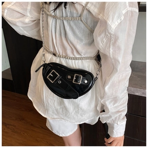 Détail du sac coeur en cuir verni noir avec boucles en métal argenté et chaîne