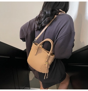 Detail of camel mini leather tote with litchi grain and cute dog leather charm