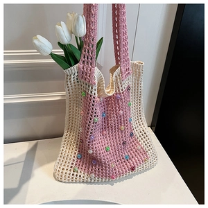 Close-up of knit tote bag with colorful beads and white tulips in soft lighting