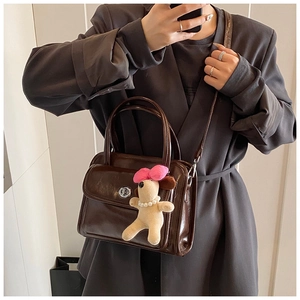 Detail of dark brown vintage crossbody bag with silver twist lock and plush puppy charm