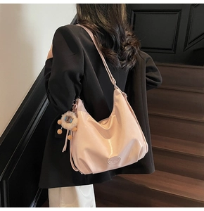 Dettaglio di una borsa hobo rosa a mezzaluna con ciondolo a forma di pecora morbida