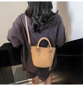 Detail of khaki leather bucket bag with puppy charm and gold-tone hardware