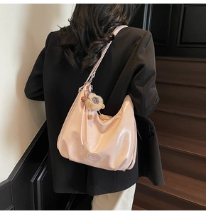 Dettaglio di una borsa tote rosa lucida con un simpatico ciondolo a forma di pecora di peluche