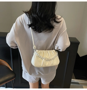 Detail shot of the cream-white ruched cloud bag with elegant pearl chain strap decoration