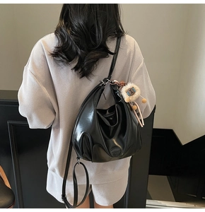 Borsa hobo nera lucida con ciondolo a forma di leone indossata da una modella